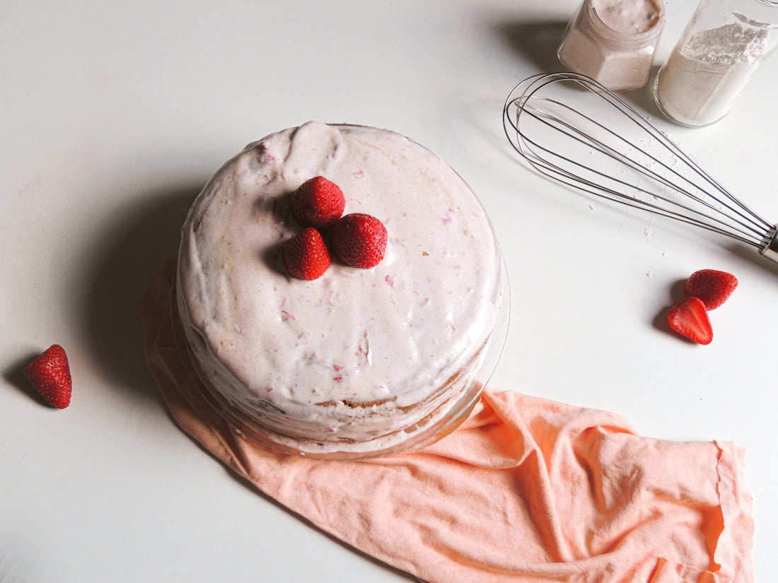 a cake sitting on top of a table next to a whisk