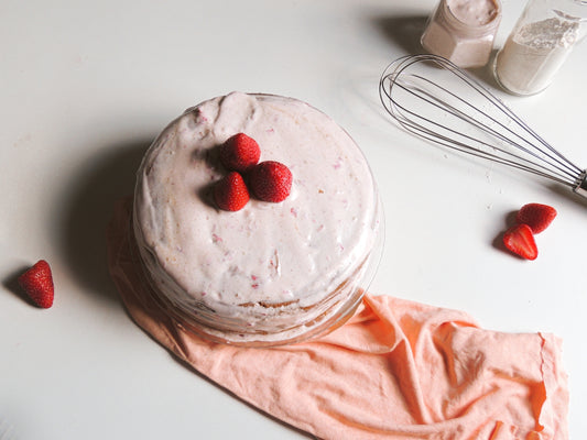 a cake sitting on top of a table next to a whisk